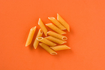 Fresh macaroni pasta on orange background. Close up
