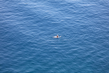 A girl swims in the blue water of the sea