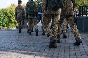 Fototapeta premium A group of soldiers are walking along the street. People in military uniform in the city. Closeup.