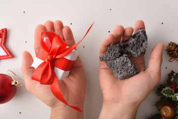 Hands with christmas gift and coal reward concept for behavior