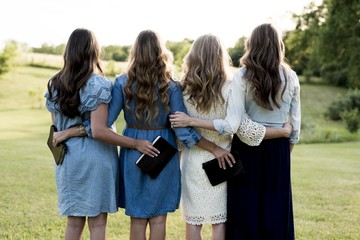 Beautiful shot of four girls with their arms around each other while holding the bible
