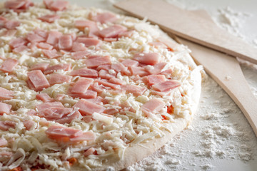 pizza de jamón sin cocinar con harina alrededor en fondo blanco
