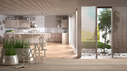 Wooden table, desk or shelf with potted grass plant, house keys and 3D letters home sweet home, over white and wooden kitchen, architecture interior design, copy space background