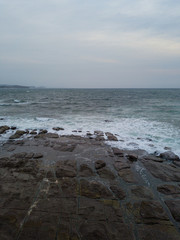 Cloudy rocky coastline view in the morning with low tide.