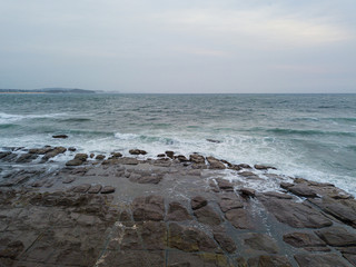 Cloudy rocky coastline view in the morning with low tide.