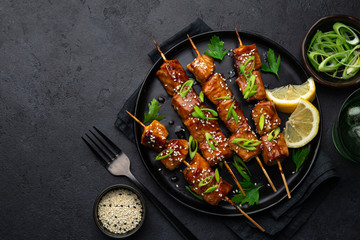 Teriyaki salmon skewers on black plate