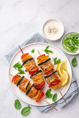 Grilled salmon and vegetables skewers on white plate