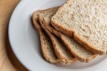 Sliced bread on white dish, wood background