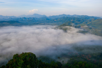 Obraz premium Aerial view of mountains with cloud cover mountain at sunrise and blue sky in Surat Thani Province, Thailand.