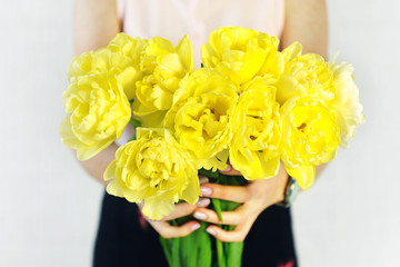 Beautiful bouquet of yellow terry tulips flowers in woman hands. Women's day, mother's day.