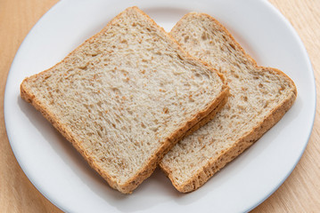 Sliced bread on white dish, wood background