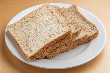 Sliced bread on white dish, wood background