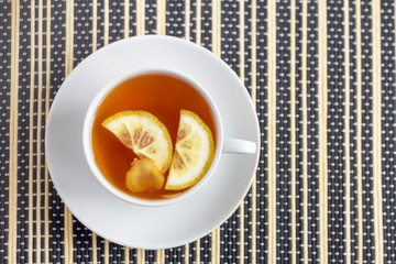a Cup of tea with lemon and ginger on a bamboo napkin, top view