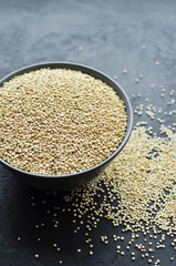 Dry organic quinoa seeds in gray ceramic plate on dark concrete background