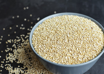 Pile of quinoa grain seeds in bowl over dark stone table background