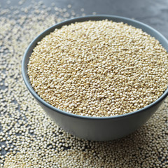 Pile of quinoa grain seeds in bowl over dark stone table background