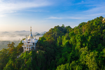 Aerial scenery of white pagoda on the mountain with cloud at sunrise in the morning in Surat Thani province, Thailand