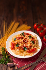 Pasta carbonara with tomato sauce and minced meat, grated parmesan cheese and fresh parsley - homemade healthy italian pasta on rustic wooden background. 