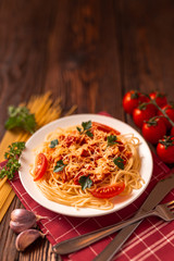 Pasta carbonara with tomato sauce and minced meat, grated parmesan cheese and fresh parsley - homemade healthy italian pasta on rustic wooden background. 