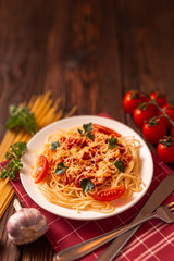 Pasta carbonara with tomato sauce and minced meat, grated parmesan cheese and fresh parsley - homemade healthy italian pasta on rustic wooden background. 