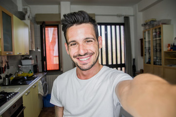 Photo of handsome man taking a selfie at home smiling on the camera