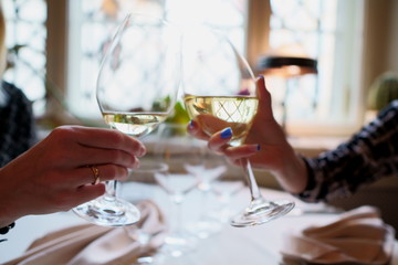 Wine glasses with white wine in a restaurant. People clink glasses of wine in a restaurant celebrating a birthday. hands without people