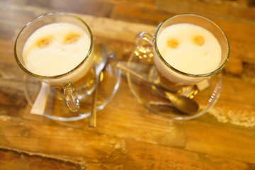 Two glass mugs with coffee latte in coffee on a vintage wooden table. Photo in dim light in warm colors on a wooden table, lifestyle photo