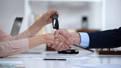 Woman signing vehicle purchase agreement, taking car keys from dealer, insurance