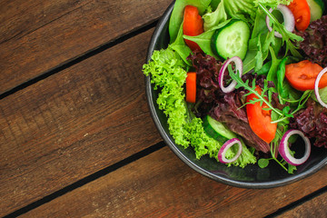 Healthy salad, leaves mix salad (mix micro greens, cucumber, tomato, onion, other ingredients) menu concept. food background. copy space. Top view