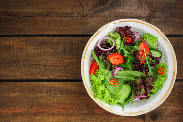 Healthy salad, leaves mix salad (mix micro greens, cucumber, tomato, onion, other ingredients) menu concept. food background. copy space. Top view