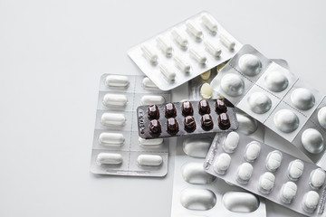 Pile of variety shape and size of medicine in its package on white table top background.