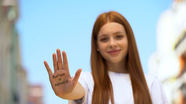 Believe in miracle phrase written on young female palm, hope and motivation