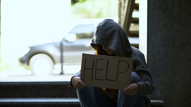Teenage girl showing help sign sitting on stairs, lost in life, needs support