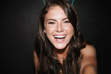 Image of brunette smiling woman holding glass while taking selfie photo