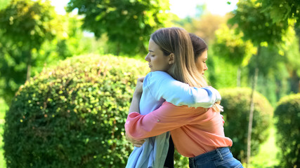 Naklejka na ściany i meble Two women hugging outdoor saying good-bye, friendship trusting relationship