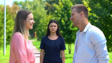 Obraz premium Smiling male and female looking each other, jealousy friend background, conflict