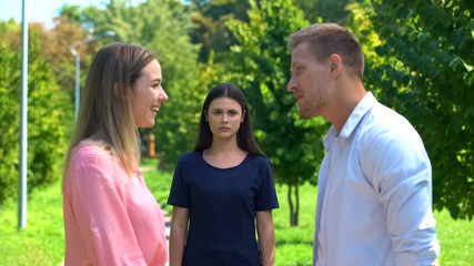 Offended female feeling lonely looking at friend talking boyfriend, jealousy