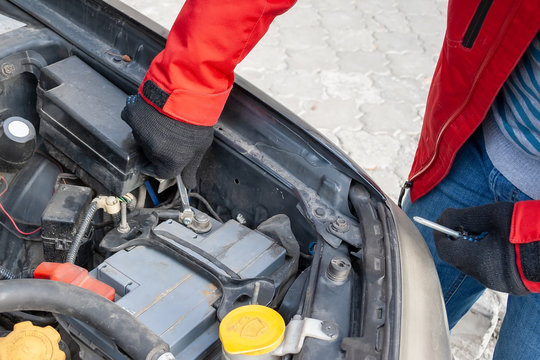 Man disconnecting the terminal on the car battery under the open hood of a Flat-four (boxer) car engine
