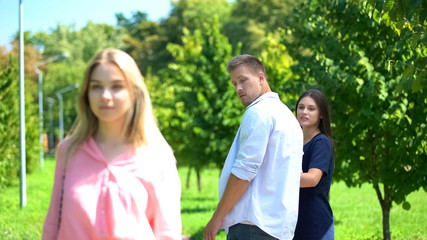 Man looking passing blond woman walking park with girlfriend, relations conflict