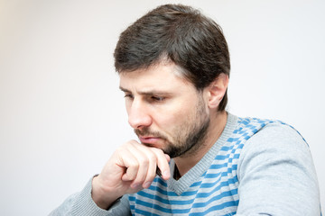 Handsome bearded man with a pen in his hand looks down thoughtfully