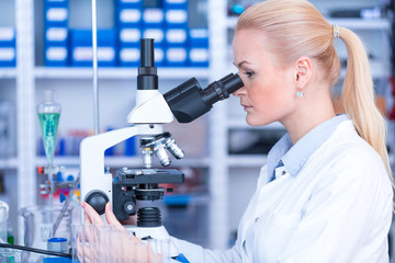 Girl with a slide for the microscope University Hospital. Attractive young scientist  looking at the microscope slide in the forensic laboratory