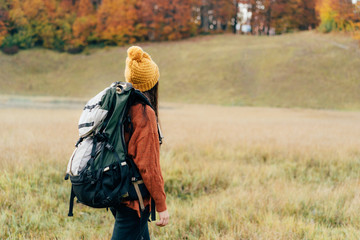 Healthy lifestyle, girl hiker with a heavy backpack in the autumn landscape.