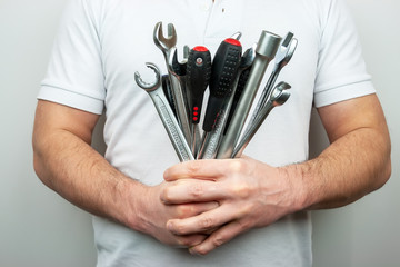 A man in a white T-shirt with a bouquet of wrenches and screwdrivers