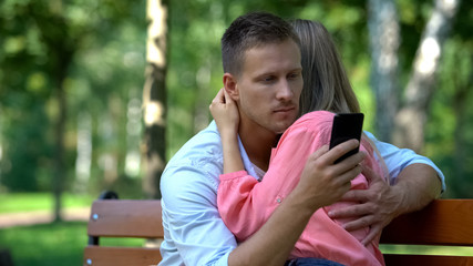 Boyfriend texting message another woman while hugging girlfriend, betrayal