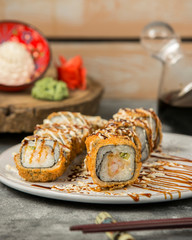hot sushi rolls with shrimp and cucumber garnished with sauce and sesame