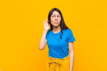 young pretty latin woman looking serious and curious, listening, trying to hear a secret...