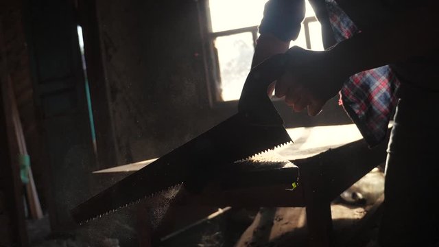 carpenter handmade and craft concept slow motion video. carpenter sawing a tree in a workshop sawing sunlight from a lifestyle window silhouette. woodworker engaged in processing wood at the sawmill