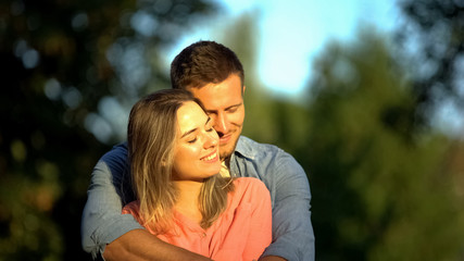 Fototapeta premium Young smiling couple hugging sunny park, candy-flower period, romantic feelings