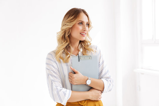 Image of caucasian secretary woman holding clipboard in white office