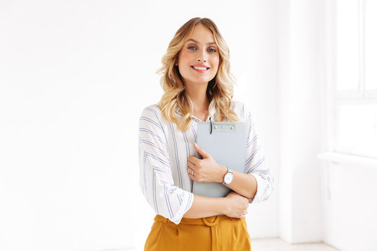 Image of attractive elegant businesswoman holding clipboard in office